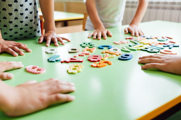 mains d'enfants déplaçant des lettres sur une table