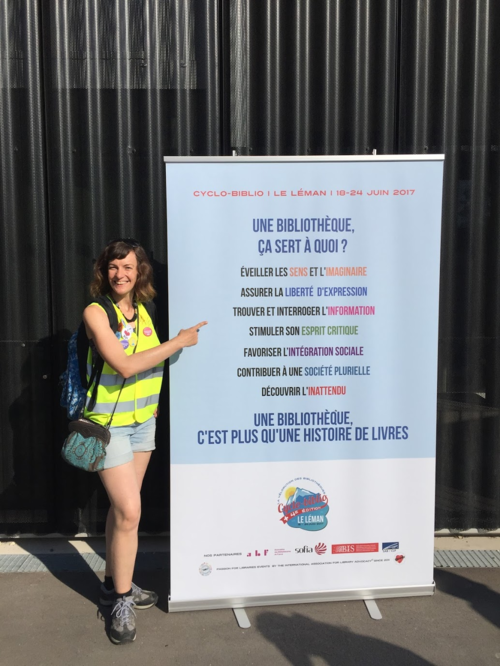 Photographie en pied de Marie Payet devant le kakémono de cyclo-biblio