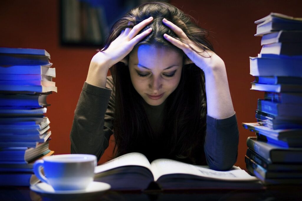 Student in a library surrounded by piles of books