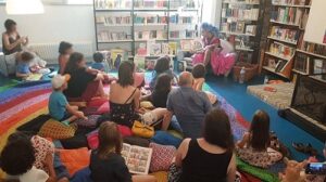 Photographie du public écoutant une lecture par un drag queen dans la bibliothèque