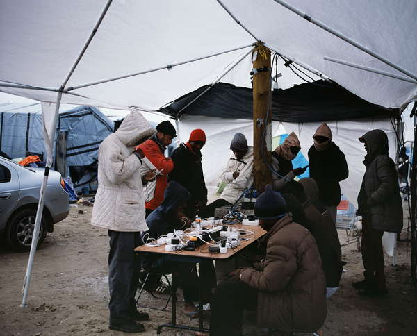 Migrants rechargeant leur téléphone sous une tente